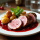 Magret de canard tranché avec sauce cerise sur assiette blanche